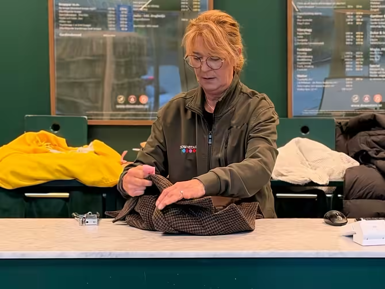 Dana vid disken i butiken i Nya Hovås, med en kavaj som just lämnats in.